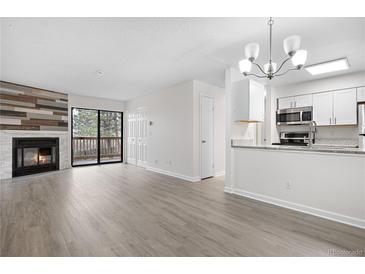 Open-concept living area featuring a fireplace, sliding glass doors, and updated kitchen with granite countertops at 14720 E Kentucky Dr # 622, Aurora, CO 80012