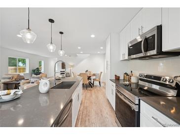 Well-lit kitchen featuring stainless steel appliances, island with sink, and adjacent dining area at 5242 Columbine Ln, Denver, CO 80221