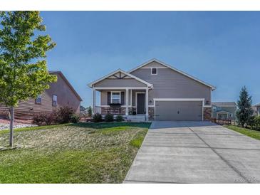 Gray exterior ranch home with stone accents, two-car garage, and landscaped lawn at 42396 Glen Abbey Dr, Elizabeth, CO 80107