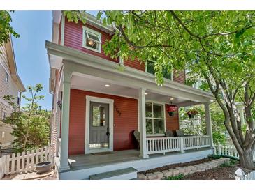 Charming red two-story home with a welcoming front porch and beautifully landscaped yard at 2737 Ulster St, Denver, CO 80238