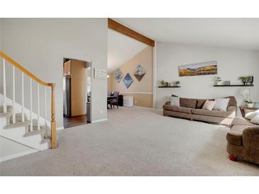 Bright living room featuring neutral paint, high vaulted ceiling with wood beam and an open floor plan at 3321 S Dunkirk Way, Aurora, CO 80013