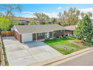 Charming brick home featuring a well-maintained lawn and long driveway with attached garage at 8353 Adams Way, Denver, CO 80221