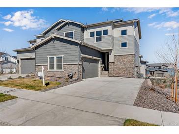 Modern two-story home featuring gray siding, stone accents, and a spacious driveway leading to an attached garage at 6863 Oak Canyon Cir, Castle Pines, CO 80108