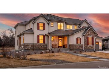 Inviting two-story home featuring stone accents, a covered porch, and warm interior lighting at 15 Latigo Pl, Littleton, CO 80123