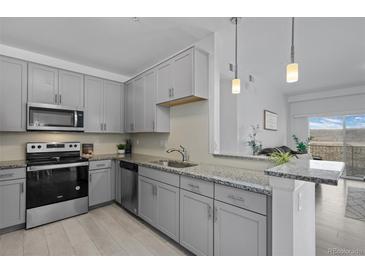 Modern kitchen featuring gray cabinets, stainless steel appliances, and granite countertops at 15700 E Jamison Dr # 8-208, Englewood, CO 80112