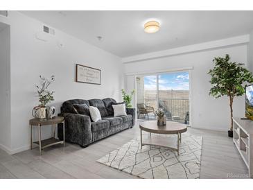 Bright living room featuring a comfortable sofa, stylish rug, and sliding glass doors to a private balcony at 15700 E Jamison Dr # 8-208, Englewood, CO 80112