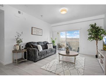 Bright living room featuring comfortable seating, stylish decor, and a sliding door to the balcony at 15700 E Jamison Dr # 8-208, Englewood, CO 80112