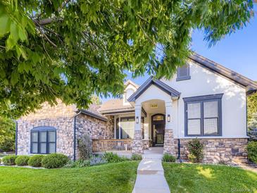 Charming front exterior with a stone and stucco facade, inviting porch, and well-manicured lawn at 1020 S Ammons Cir, Lakewood, CO 80226