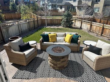 Cozy backyard featuring a stone fire pit, comfortable seating, and a well-maintained lawn at 3173 Youngheart Way, Castle Rock, CO 80109
