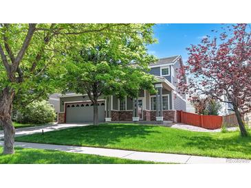 Charming two-story home with a well-manicured lawn, mature tree, and inviting front porch at 19730 E 58Th Pl, Aurora, CO 80019
