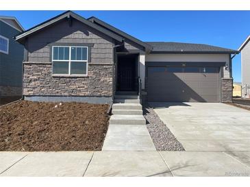 Charming one-story home featuring stone accents, a two-car garage, and a well-manicured front yard at 3911 N Shawnee St, Aurora, CO 80019