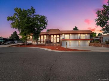 Charming multi-level home with well-maintained yard, three-car garage, and inviting curb appeal at dusk at 8233 W 62Nd Pl, Arvada, CO 80004