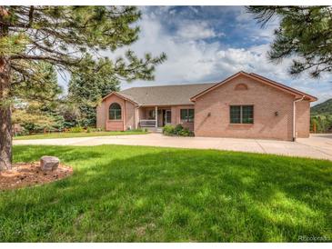 Charming brick home featuring a circular driveway and well-manicured lawn at 1660 Old Antlers Way, Monument, CO 80132