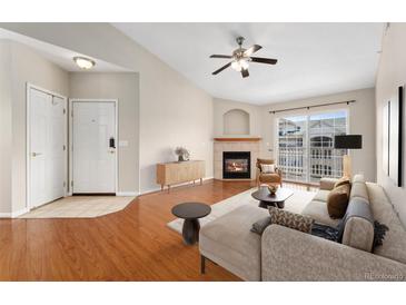 Inviting living room boasts a cozy fireplace, modern ceiling fan, and access to outdoor balcony at 7440 S Blackhawk St # 7-303, Englewood, CO 80112