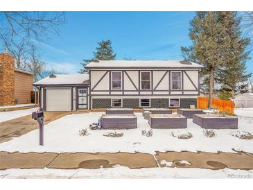 Snow-covered ranch home with a two-car garage and garden beds at 16193 E Dickenson Pl, Aurora, CO 80013