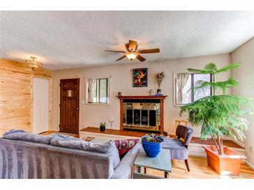 Cozy living room features a wood-burning fireplace, ceiling fan, and lots of natural light at 1275 Niagara St, Denver, CO 80220