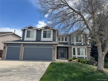 Charming two-story home featuring a three-car garage, blue siding, brick accents, and a well-manicured lawn at 452 Bexley Ct, Highlands Ranch, CO 80126