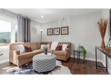 Inviting living room featuring a comfortable sofa, stylish ottoman, and a large window for natural light at 3541 E 118Th Ave, Thornton, CO 80233