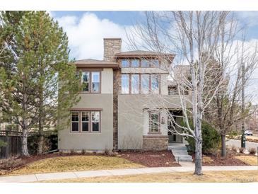 Inviting two-story home featuring a stone chimney and beautifully framed windows, surrounded by lush landscaping at 8806 E 35Th Ave, Denver, CO 80238