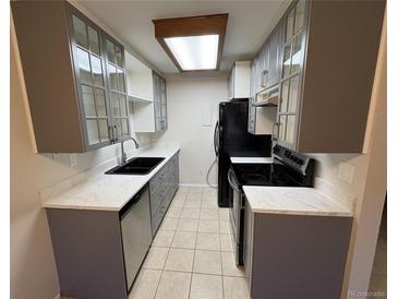 Galley kitchen with ample cabinetry, including glass-front cabinets, and sleek, white countertops at 14751 E Tennessee Dr # 213, Aurora, CO 80012