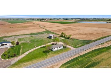 Expansive aerial view of a charming country home with lush green lawns and surrounding farmland at 19810 County Road 1, Berthoud, CO 80513