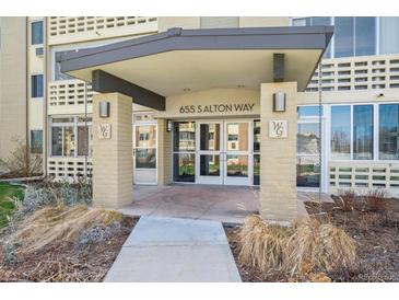 Building entrance featuring a covered entryway with glass doors, brick columns, and well-maintained landscaping at 655 S Alton Way # 4B, Denver, CO 80247
