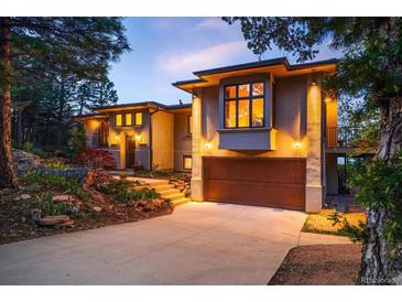 Beautiful home with a lush landscape, large driveway, and garage entrance on a sunny day at 8932 Eastridge Rd, Golden, CO 80403