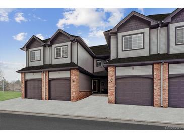 Three-unit townhome building with attached garages and brick accents at 10810 W 63Rd Ave # C, Arvada, CO 80004