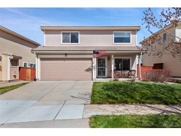 Charming two-story home featuring a tile roof, an attached garage, a front porch, and manicured lawn at 4056 Perth St, Denver, CO 80249