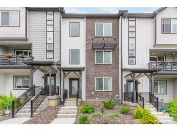 Modern townhome exterior showcasing gray and white siding with brick accents, complemented by well-maintained landscaping at 1918 W 165Th Way, Broomfield, CO 80023