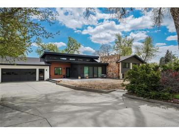 Contemporary home with a dark exterior, stone chimney, and an attached two-car garage at 6260 Lamar St, Arvada, CO 80003