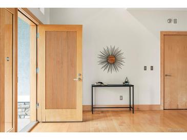 Bright entryway with an open front door, light wood floors, modern table and decorative art at 1942 Kentmere Dr, Longmont, CO 80504