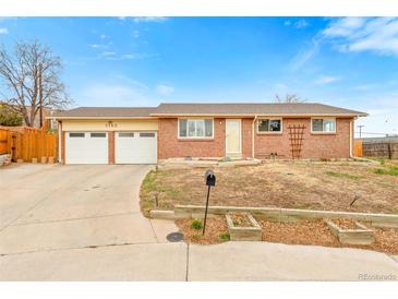 Charming brick home featuring an attached two-car garage and well-maintained front yard at 7162 Quay St, Arvada, CO 80003
