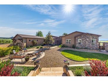 Stunning backyard with stone firepit, inviting seating area, and beautiful landscaping, perfect for outdoor gatherings at 11784 Spruce Mountain Rd, Larkspur, CO 80118