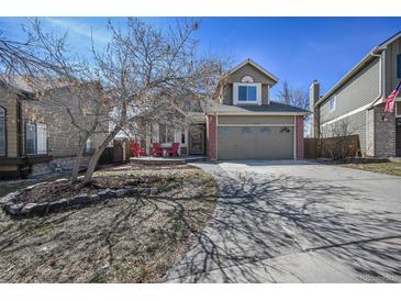 Charming home featuring a two-car garage, red chairs on the front porch, and a well-manicured yard at 9443 Palisade Ct, Highlands Ranch, CO 80130