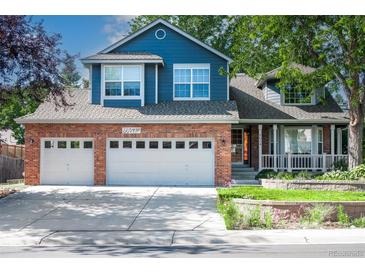 Charming two-story home with brick accents, a well-manicured lawn, and a two car garage at 6054 W Adriatic Pl, Lakewood, CO 80227
