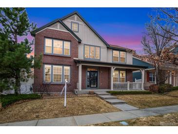 Charming brick home featuring a cozy front porch and well-manicured lawn at 13744 W 86Th Dr, Arvada, CO 80005