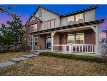 Charming two-story brick home with a welcoming front porch and manicured lawn at 13744 W 86Th Dr, Arvada, CO 80005
