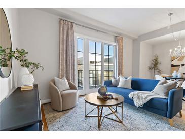 Bright living room features a modern blue sofa, round wooden table, and large windows with access to a private balcony at 410 Acoma St # 309, Denver, CO 80204