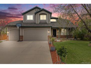 Charming two-story home featuring a two-car garage, well-manicured lawn, and colorful dusk sky at 17522 E Dewberry Dr, Parker, CO 80134