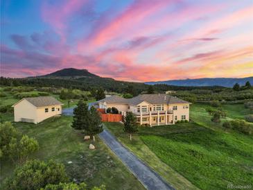 Stunning aerial view of home featuring a landscaped yard, long driveway, guest house, and beautiful sunset backdrop at 3485 Park Ridge Rd, Sedalia, CO 80135