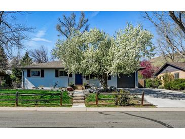 Charming home featuring blooming tree, well-kept lawn, and inviting entrance, with attached garage and driveway at 2435 Creighton Dr, Golden, CO 80401