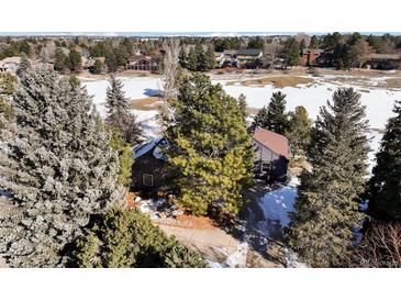 Aerial view of house on a snowy landscape, with a lake and other houses visible in the background at 7863 Windfont Row, Parker, CO 80134