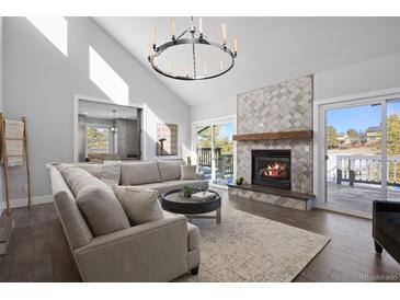 Spacious living room featuring a cozy fireplace and large windows at 7863 Windfont Row, Parker, CO 80134