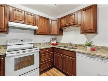 Well-lit kitchen features wood cabinetry, stone counters, and modern white oven and dishwasher at 610 S Alton Way # 8D, Denver, CO 80247