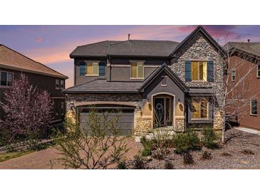 Beautiful two-story home with stone accents, gray siding, a gray roof, and manicured landscaping at 7033 E Lake Cir, Centennial, CO 80111