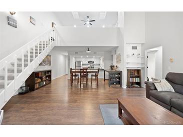Bright open-concept living room with wood floors, staircase, and direct access to the kitchen and dining area at 23551 Genesee Village Rd # H, Golden, CO 80401