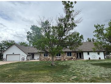 Charming home featuring stone accents, mature trees, and a spacious front yard at 22400 County Road 10, Hudson, CO 80642