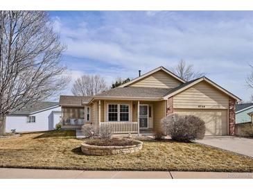 Tan exterior house with a well-manicured lawn and attached garage at 9748 W Peakview Dr, Littleton, CO 80123