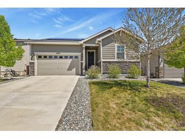 Charming single-story home featuring a two car garage, stone accents, manicured lawn, and solar panels at 16099 Alberta Dr, Parker, CO 80134